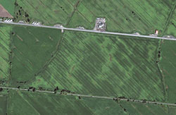Vue aérienne de champs montrant des zones de couleur variant du vert foncé à vert pâle.