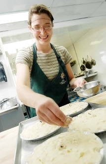 Jeune femme effectuant une dernière touche à la préparation de plats dans une cuisine commerciale
